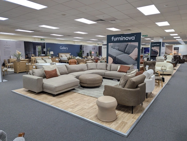 an island exhibition stand showing a range of sofas and chairs with a freestanding wall behind them
