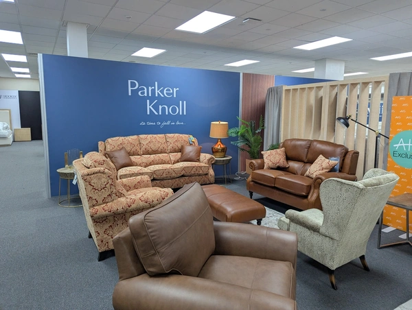 a blue back wall with two sofas and three chairs sitting in front, in an exhibition hall in solihull